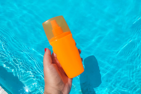 Spray sunscreen stands on the background of the poolの写真素材