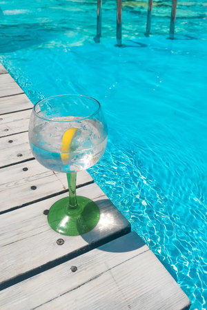 Cocktail with lemon tonic on blue pool background