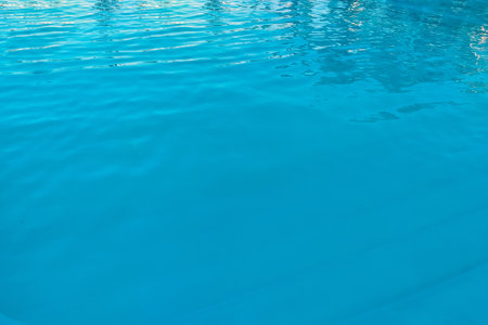 Azure transparent texture of water in a blue pool with splashes from the sunの写真素材