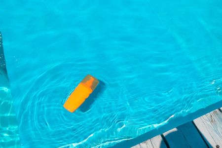 Spray sunscreen stands on the background of the pool