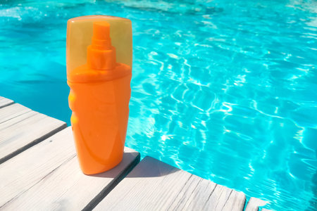 Spray sunscreen stands on the background of the pool
