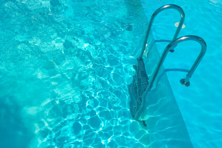 Staircase in the swimming pool with blue water in the backgroundの写真素材