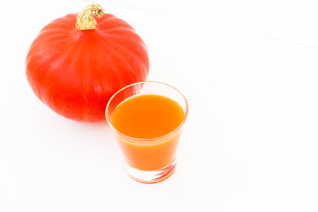 A glass of orange juice with a pumpkin on a light backgroundの写真素材