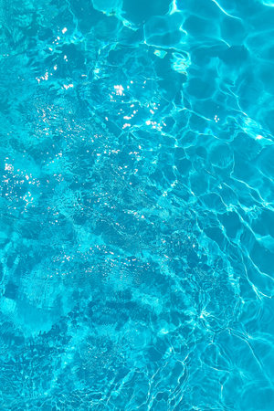 Azure transparent texture of water in a blue pool with splashes from the sun
