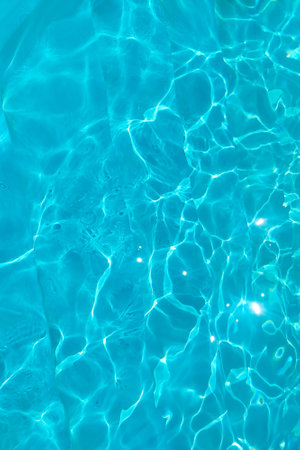 Azure transparent texture of water in a blue pool with splashes from the sunの写真素材