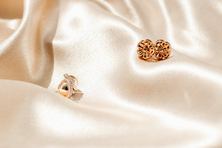 Gold earring decoration on golden silk fabric with space for textの写真素材