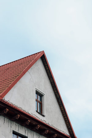 red roof of a house with windows on the background of a blue skyの写真素材