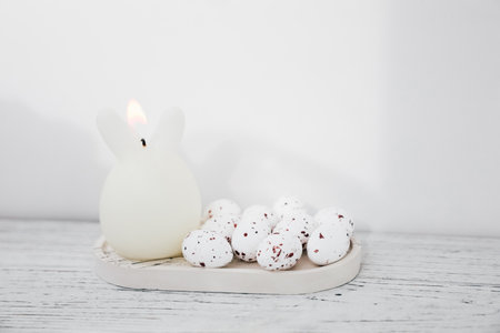 white candle bunny with speckled eggs on a wooden surface for Easter celebrationの写真素材