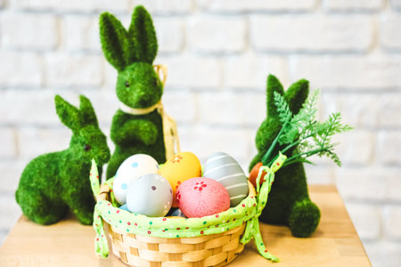 Decorative bunnies made of green material surround a basket filled with pastel-colored Easter eggs....