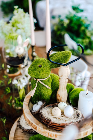 A festive spring table showcases a moss-covered bunny beside decorative eggs and plants, evoking Easter joy.の写真素材