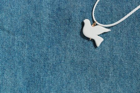 white bird made of polymer clay on the background of denim fabric