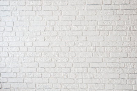 A simple white brick wall displays a textured surface, providing a clean and modern background suitable for various uses and settings.の写真素材