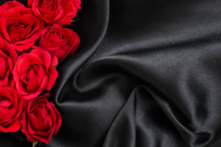 Beautiful red roses on elegant black silk fabric create a stunning visual compositionの写真素材