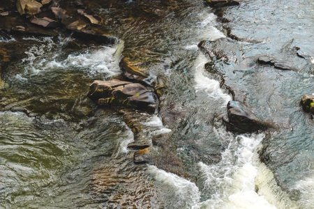 Gentle river currents wind through rocky formations creating a tranquil atmosphere under bright sunlight.の写真素材