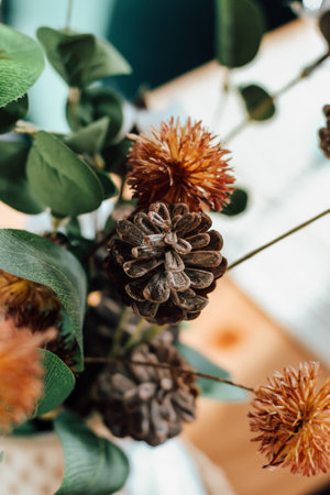 A stunning floral composition featuring dried flowers and pinecones brings warmth to the cozy interior accentuating natural aesthetics.の写真素材