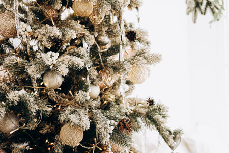 A snowy Christmas tree decorated with golden ornaments and pinecones creating a festive and warm atmosphere in winter.の写真素材