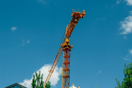 A tall construction crane stands prominently against a clear blue sky surrounded by modern buildings...