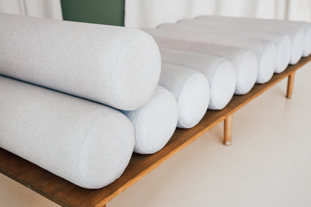 Soft gray bolsters are aligned on a wooden table in a tranquil yoga studio.の写真素材