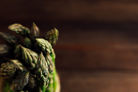 Green asparagus spears are elegantly arranged against a dark wooden surface showcasing their vibrant color and texture.の写真素材