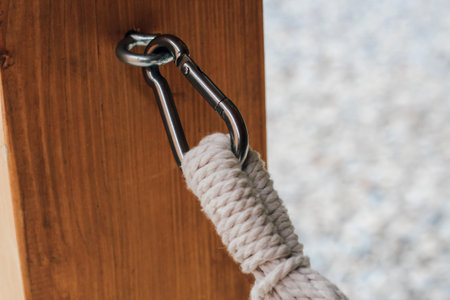 A sturdy rope is fastened to a metal clip attached to a wooden post showcasing secure outdoor rigging techniques during daylight.の写真素材