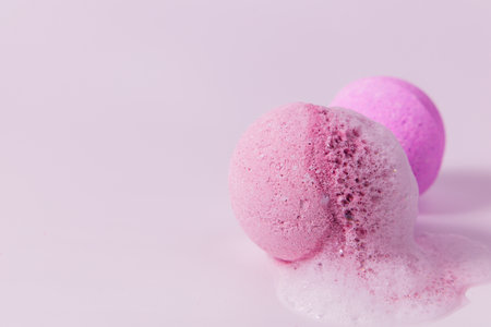 Two vibrant bath bombs in shades of pink are fizzing on a soft pink background creating a soothing ambiance and bubbly texture.の写真素材