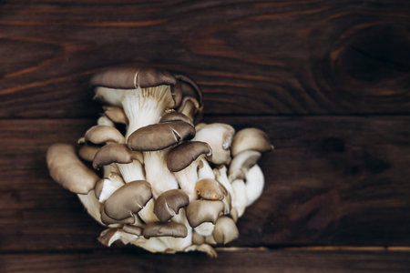 Clusters of fresh mushrooms display an organic arrangement on a wooden table showcasing their unique shapes and textures.の写真素材