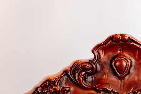 Focus on the elaborate carvings of a vintage wooden chair against a plain background highlighting craftsmanship and artistry.の写真素材
