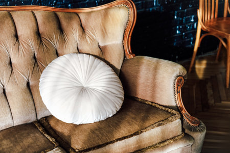 A stylish beige sofa features a round white decorative pillow creating a cozy atmosphere in a contemporary room.の写真素材