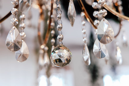 Intricate crystal droplets dangle gracefully from a chandelier reflecting light in a stylish indoor environment.の写真素材