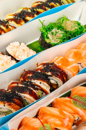 Sushi rolls with various toppings and fillings are beautifully presented on a platter showcasing a variety of colors and textures.の写真素材