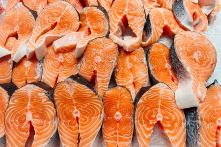 Brightly colored salmon fillets are neatly arranged for sale at a local market. Customers can find...