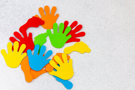 A variety of colorful hand shapes made from foam are scattered across children's creativity applique