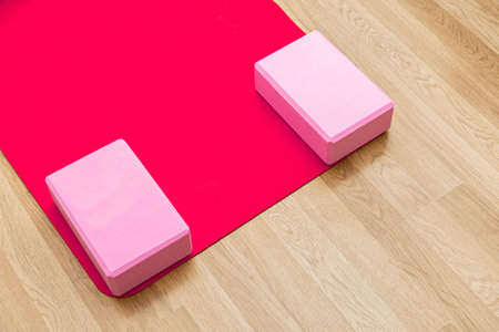 Bright studio features a red yoga mat and two pink blocks arranged for a yoga session creating a calm atmosphere for practice.の写真素材