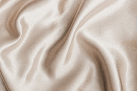 This soft satin fabric displays delicate folds and sheen reflecting light beautifully in a neutral tone.の写真素材