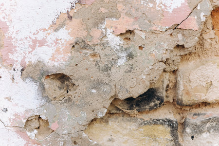 The wall features significant damage with peeling paint exposed bricks and patches of dirt. This shows age and neglect over time.の写真素材