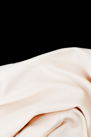 Soft silk fabric drapes playfully showcasing its delicate texture and natural sheen on a dark backdrop creating a striking contrast.の写真素材