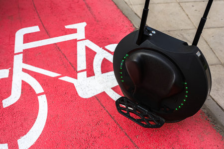 An electric unicycle rests beside a bike lane marking in a busy city highlighting innovative urban mobility choices.の写真素材
