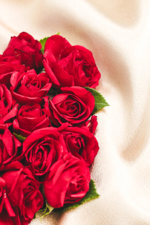 A beautiful arrangement of fresh red roses is placed on soft textured fabric.の写真素材