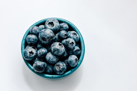 Plump blueberries fill a turquoise bowl showcasing their rich color and texture. Perfect for snacks or desserts.の写真素材