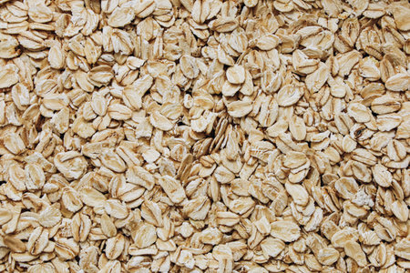 Raw oats are laid out in a natural pattern showcasing their unique shapes and textures. The light reflects subtly enhancing their earthy tones.の写真素材