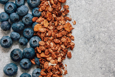 Fresh blueberries and crunchy granola are artfully arranged on a gray surface creating a visually appealing and nutritious breakfast option.の写真素材