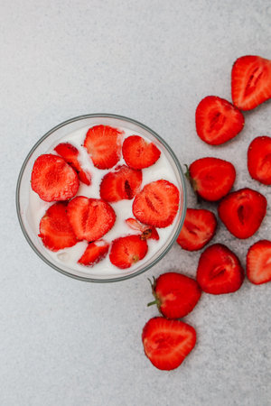 A bowl filled with creamy dessert topped with fresh strawberry slices surrounded by whole strawberries.の写真素材