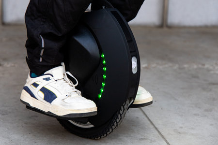 A person balances on a unicycle equipped with green lights enjoying a ride on a warm urban day while...