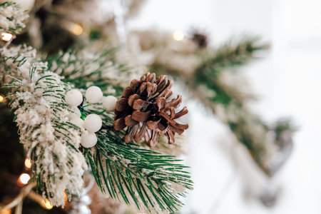 Close up view of a decorated winter pine tree branch adorned with a pinecone and white berries showcasing festive colors and textures.の写真素材
