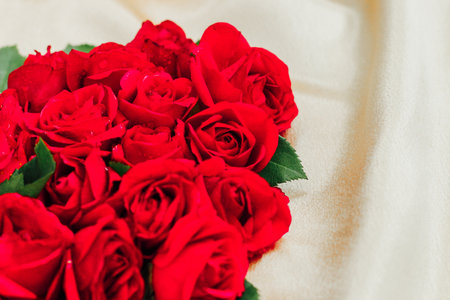 Fresh red roses are arranged artistically in the shape of a heart on soft fabric creating a romantic setting for a special event.の写真素材