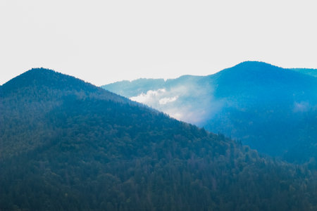Morning light illuminates misty mountains revealing lush greenery and rolling hills in a serene landscape setting.の写真素材