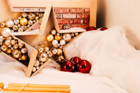 Decorative star filled with shiny ornaments sits among soft white fabric and red balls creating a festive atmosphere.の写真素材