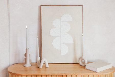 A minimalist decor featuring abstract artwork and elegant candles on a wooden console table creates a warm atmosphere.の写真素材