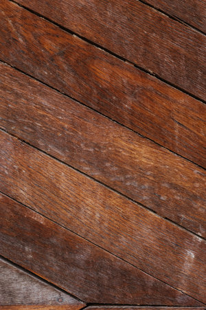A chevron patterned wooden floor displays a mix of rich browns and warm tones highlighting the natural grain and texture in soft lighting.の写真素材