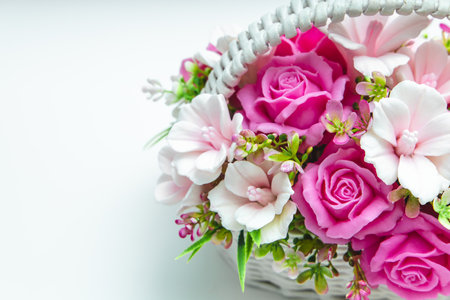 This floral arrangement features pink roses and white blossoms elegantly displayed in a woven basket.の写真素材